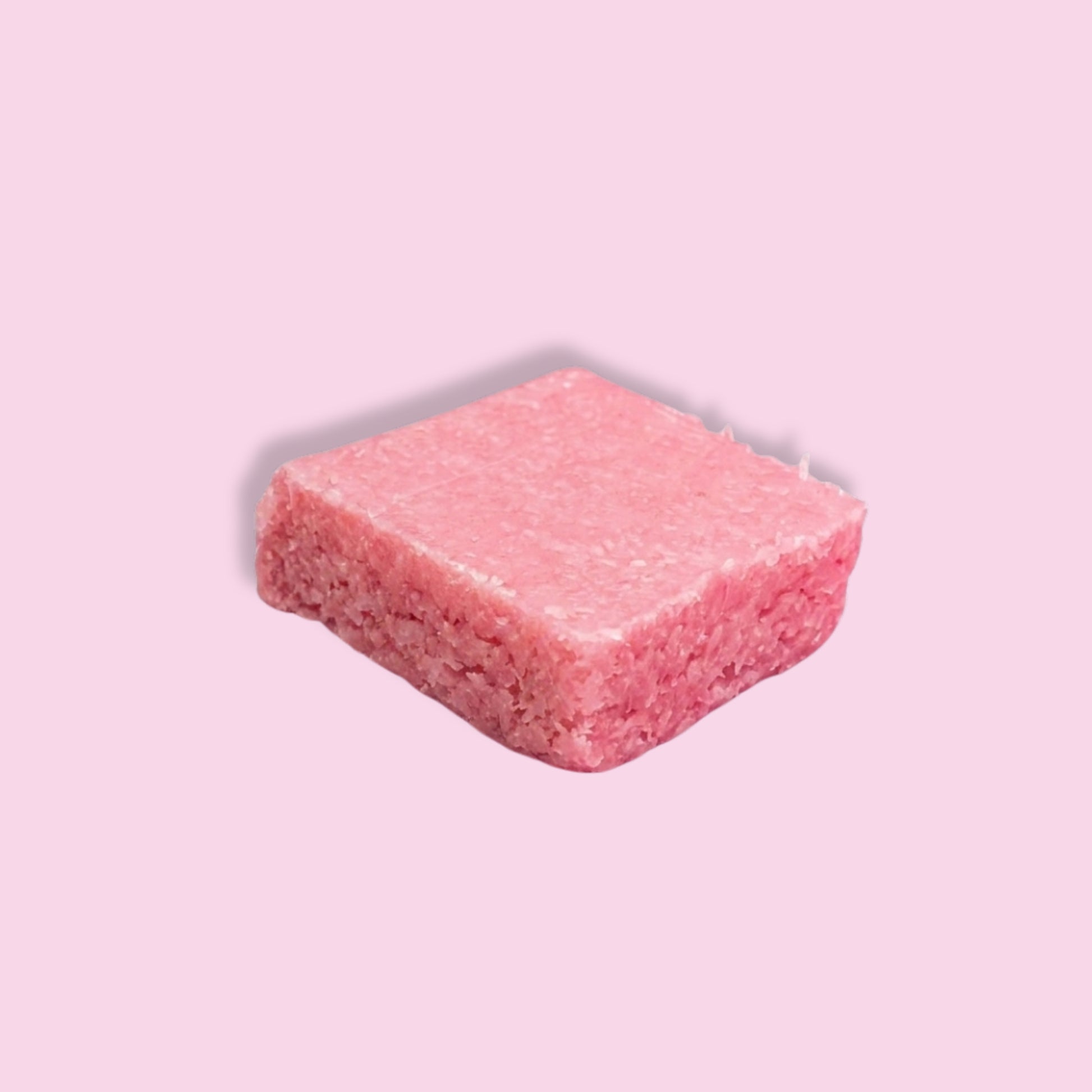 A single pink rectangular block, resembling a compressed sponge or textured sponge cube, shown on a solid light pink background.